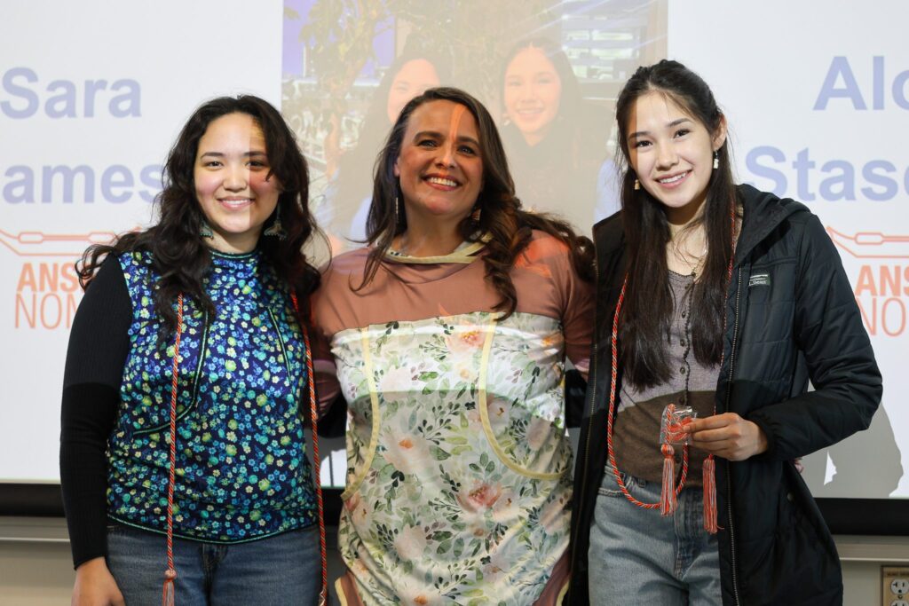 ANSEP seniors Sara James (left) and Alora Stasenko (right) posing with program director Kacey Miller (middle) after receiving their ANSEP cords. Quinn White/KNOM